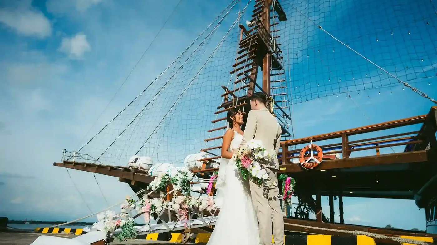Bride and groom with flowers beside a traditional phinisi in Bali
