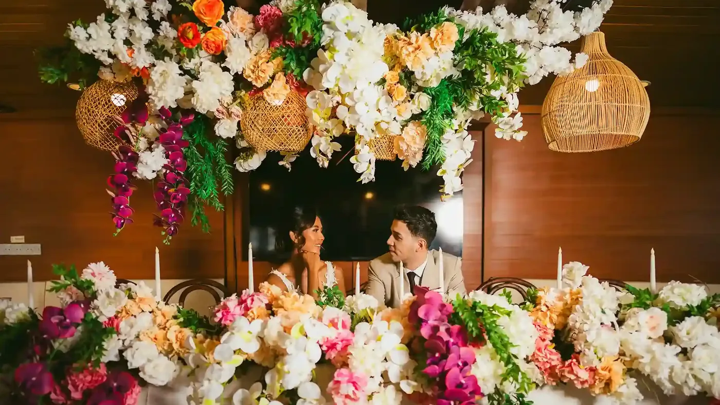 Floral ceremony setting with lanterns and a couple seated behind it in Bali